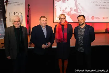 Cztery osoby pozują do zdjęcia na scenie podczas prezentacji archiwalnego filmu z 1958 roku w bibliotece.