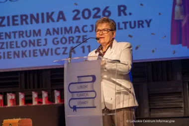 Kobieta w białej marynarce przemawia zza przezroczystego pulpitu podczas konferencji w Centrum Animacji Kultury w Zielonej Górze.