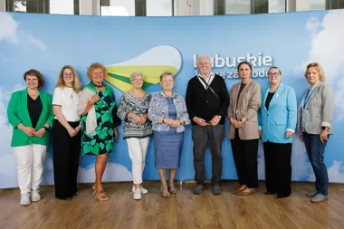 Grupa dziewięciu osób pozuje do pamiątkowego zdjęcia przed niebieskim tłem promocyjnym z napisem „Lubuskie”.